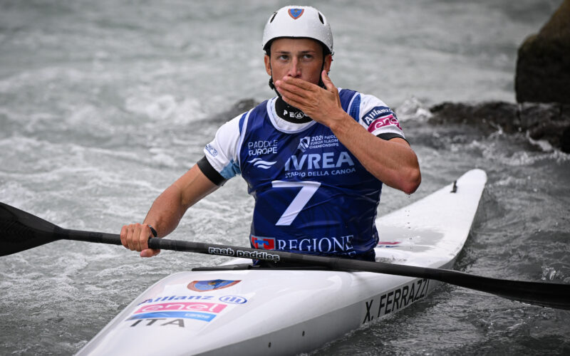 Atleta italiano di canoa slalom con medaglia e abbigliamento nazionale durante un evento sportivo sull'acqua.