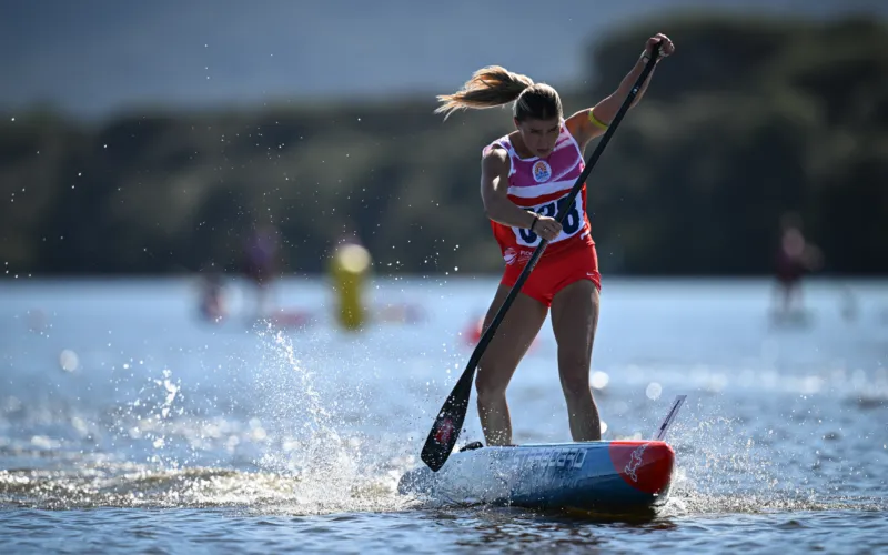 Fotografia illustrativa di una ragazza che corre in SUP su un lago, con altri concorrenti sullo sfondo.