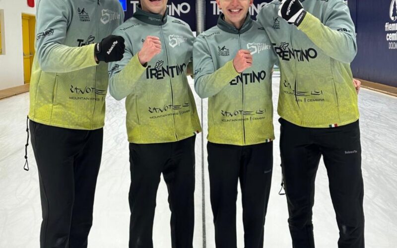 Quattro giocatori di curling del Team Spiller posano con il pugno alzato e sorridenti sul ghiaccio di una pista da curling.