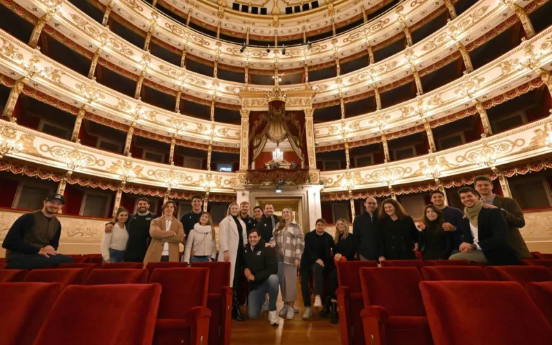 Immagine di un teatro con pubblico e orchestra in una sala elegante, simbolo di cultura e collaborazione.