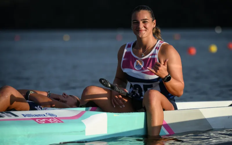 Foto di archivio di Claudia Postiglione durante una competizione di SUP, sorridente con medaglia, in barca sull'acqua.