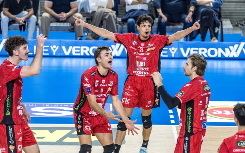 Fotografia di una partita di pallavolo con giocatori in maglietta rossa che celebrano un punto.