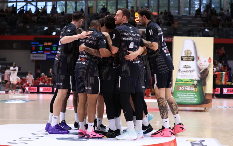 Immagine illustrativa di una squadra di basket in abbigliamento scuro durante un momento di gioco o di momento di gruppo in campo.